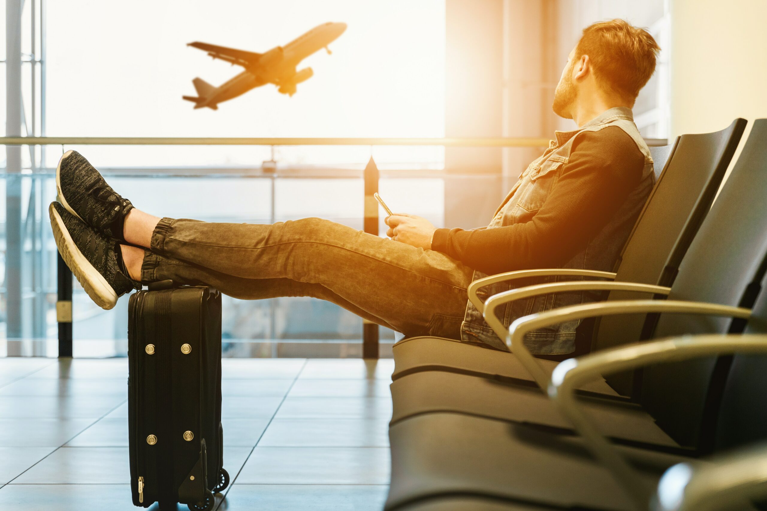 En mann som sitter og venter på sitt neste fly etter en besilt reise med sitt kredittkort.